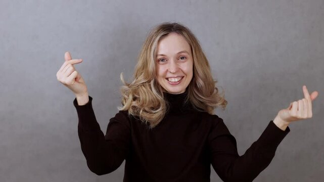 ancing in front of camera on gray background, showing heart with hands