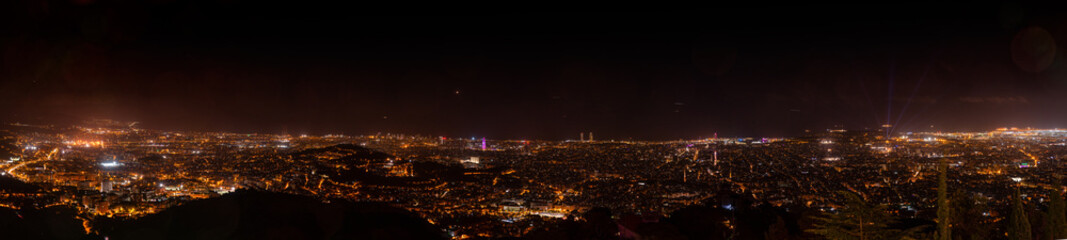A stunning panoramic night view of Barcelona from Tibidabo, Catalonia, Spain, showcasing the illuminated cityscape, iconic landmarks, and a vibrant urban glow stretching into the horizon.