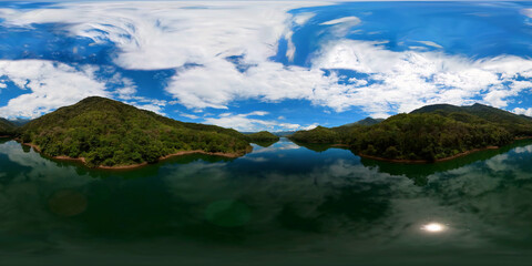 Aerial view of lake among green hills and mountains with tropical vegetation.