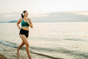Young woman running or jogging on the beach at sunset	
