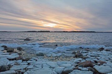 View of sunset from snow and ice covered rocky seashore on a cold winter day, Lauttasaari, Helsinki, Finland.