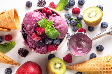 Homemade fruit and berry sorbet ice cream, portioned bowl with healthy fruit and berry yogurt gelato with fresh blueberry, raspberry, strawberry, blackberry, apples, kiwi on kitchen table