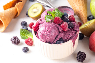 Homemade fruit and berry sorbet ice cream, portioned bowl with healthy fruit and berry yogurt gelato with fresh blueberry, raspberry, strawberry, blackberry, apples, kiwi on kitchen table