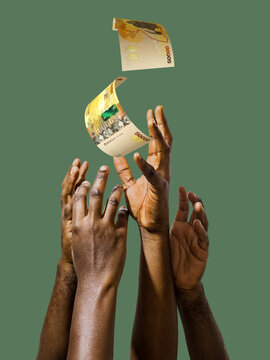 Many black African hands reaching out for Ugandan shilling notes money over green background. Stretching arms for cash