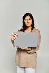 Fototapeta premium Brunette young woman showcasing confidence in a studio in a beige sweater