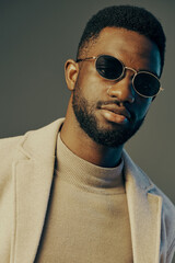Fototapeta premium Stylish man wearing sunglasses and a beige coat, exuding confidence and trendiness in a modern urban setting with a cool color palette