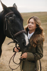 Obraz premium Woman in Elegant Tweed Outfit Bonding With a Black Horse in a Field