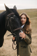 Obraz premium Elegant Woman in Tweed with Black Horse in Countryside Setting