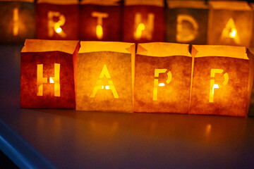 cardboard boxes illuminated with candles inside with letters cut out with the construction of the word happy birthday