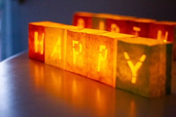 cardboard boxes illuminated with candles inside with letters cut out with the construction of the word happy birthday