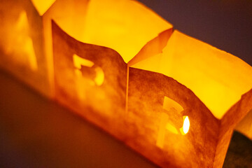 cardboard boxes illuminated with candles inside with letters cut out with the construction of the word happy birthday