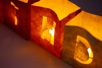 cardboard boxes illuminated with candles inside with letters cut out with the construction of the word happy birthday