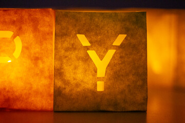 cardboard boxes illuminated with candles inside with letters cut out with the construction of the word happy birthday