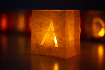 cardboard boxes illuminated with candles inside with letters cut out with the construction of the word happy birthday