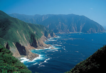Fototapeta premium Aerial view of the coast and islands near ลshima in Japan, featuring rugged cliffs and pristine beaches. The ocean is turquoise with gentle waves breaking on rocky shores surrounded by lush 