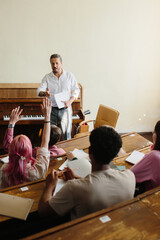 Teacher Engaged with Students in Classroom Interaction During Lesson at Wooden Desks