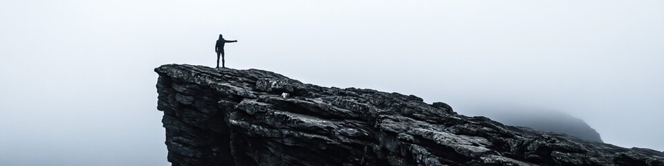 Obraz premium Person on Rocky Outcrop in Fog