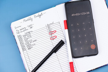 Open daily planner notebook and calculator on desk, with organized Monthly Budget tracking. With...