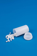 Homeopathy alternative medicine concept with classic homeopathic globules on a blue background. Emphasizing natural healing, holistic health, and eco-friendly remedies in alternative medicine.