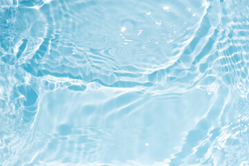 Blue water with ripples on the surface. Defocus blurred transparent blue colored clear calm water surface texture with splashes and bubbles. Water waves with shining pattern texture background.