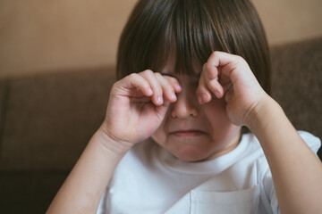 Fototapeta premium Toddler boy kid is crying. The face of a cute little upset five year old baby boy in tears. Children grief.