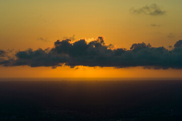Sunset sky over dark land. Bright colorful orange and yellow clouds. Panoramic skyscape
