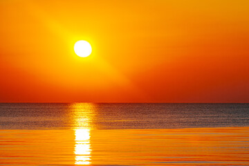 A mesmerizing sunset over the ocean, casting golden and orange hues across the sky and water. The sun’s reflection creates a serene and warm atmosphere.