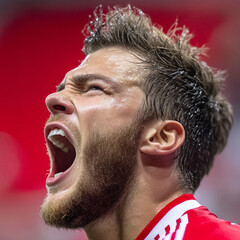 Obraz premium Emotional soccer player celebrates victory with a loud roar during a match in a vibrant stadium at night