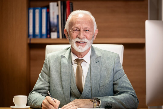 Portrait of caucasian bearded businessman sitting in his luxury office.