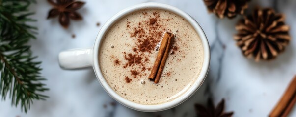 Warm chai latte with cinnamon and pine cones on marble background