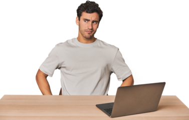 Hispanic young man working on laptop confused, feels doubtful and unsure.