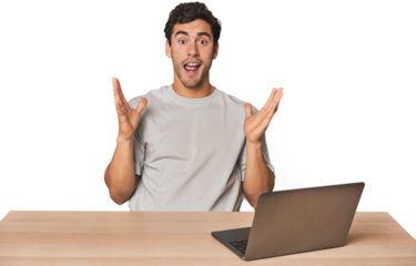 Hispanic young man working on laptop celebrating a victory or success, he is surprised and shocked.