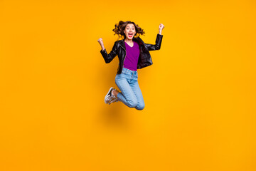 Obraz premium Full body photo of cheerful cute girl raise her fists scream yeah jump celebrate achievement wear denim jeans outfit isolated over yellow color background