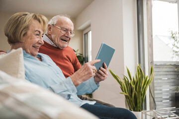 Happy senior couple using tablet PC at home