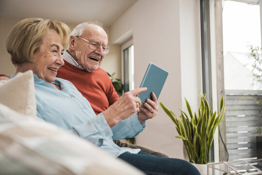 Happy senior couple using tablet PC at home