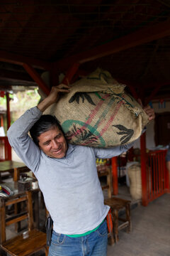 A farmer in Salento, Colombia, carrying a sack of coffee indoors.