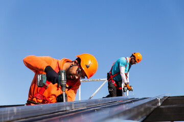 Construction workers drilling metal structure on rooftop under blue sky