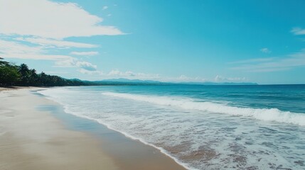 Fototapeta premium Tranquil Beach Scene: Ocean Waves on Sandy Shoreline with Distant Mountains