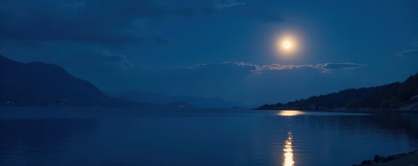 Dark blue evening sky reflects soft glow of full moon, glowing moonbeams, peaceful atmosphere, gentle reflection