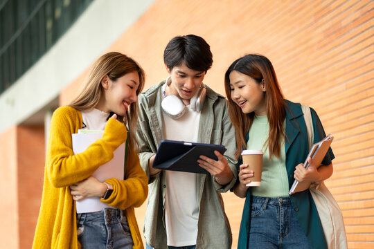 Students at university with fun for learning,Walking,laughing and bonding and talking.asian group of gen z friends student giving high five outdoor with books ready for education at college campus.