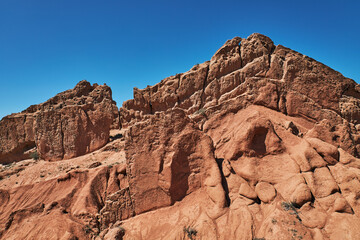 Fototapeta premium Fairy Tale Canyon on the southern shore of Issyk-Kul lake, Kyrgyzstan. Picturesque travel destination, landmark Kirgiziya. Summer skazka canyon with colorful rocks and hills. Natural park landscape