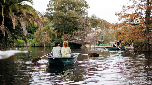 Lesbian couple rowing boat near trees in lake at Ciutadella Park, Barcelona, Spain