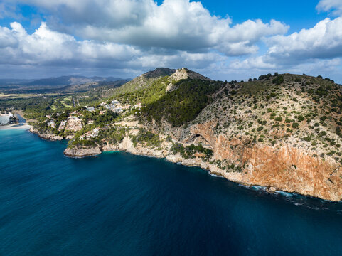 Aerial view of the coastline in Capdepera, Mallorca, featuring Cuevas de Arta and Platja de Canyamel under a cloudy sky.