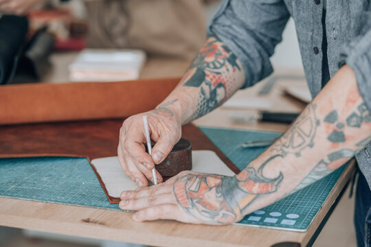 Businessman measuring leather patch at workbench