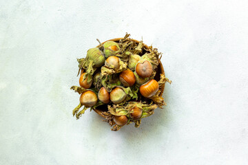 Fresh hazelnuts with leafy shells in wooden bowl, top view. harvest time