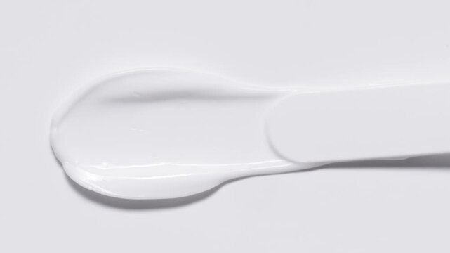 Close up of spatula smear cream texture, texture stroke isolated on white background. Cosmetic product swatch