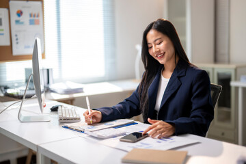 A woman is sitting at a desk with a computer monitor and a keyboard