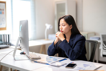 Obraz premium A woman is sitting at a desk with a computer monitor in front of her