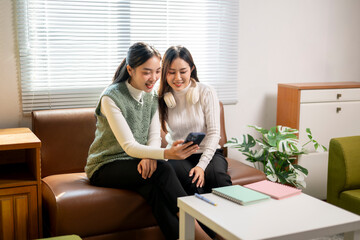 Two women sitting on a couch, one of them looking at her phone