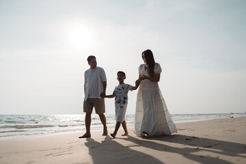 Happy asian family enjoy together on the beach in holiday vacation. family holding hands enjoying the sunset on the sea beach. Happy family travel, trip  family holidays weekend.